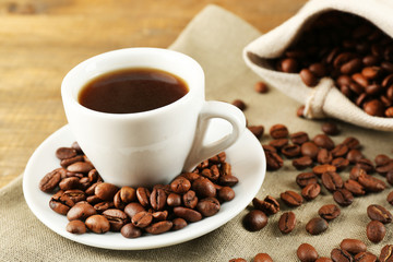 Cup of coffee with beans on rustic wooden background