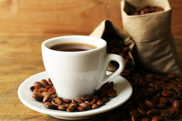 Cup of coffee with beans on rustic wooden background
