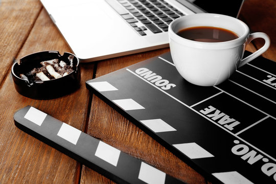 Movie clapper with laptop and cup of coffee on wooden background