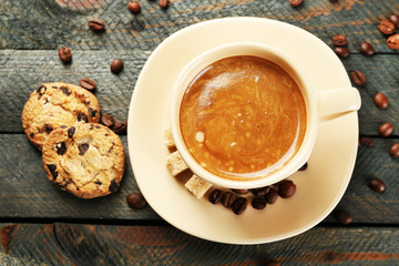 Cup of coffee and tasty cookies on wooden background