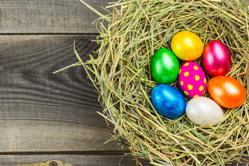 Easter eggs in the nest on rustic wooden background