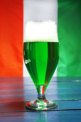 Glass of green beer on Ireland flag background