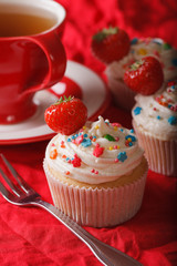 cupcakes with strawberries and a cup of tea. vertical