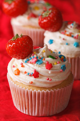 upcakes with cream and fresh strawberries close up. vertical