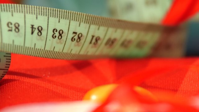 Measuring tape isolated on red cloth, close up