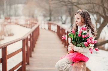 spring outdoor portrait of beautiful child girl with tulips
