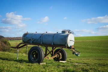 Viehweide, abgestellter, alter Wagen mit Wasserfass