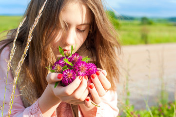 Beauty of nature. Young beautiful girl smelling meadow clover fl