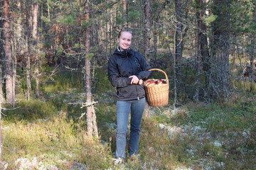 Young woman with a basket of cepes mushrooms in the forest