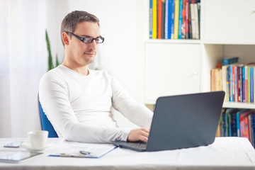 Young businessman working at home using laptop