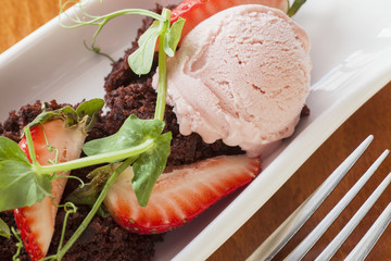 dessert of crumbled chocolate cake, gelato and strawberries