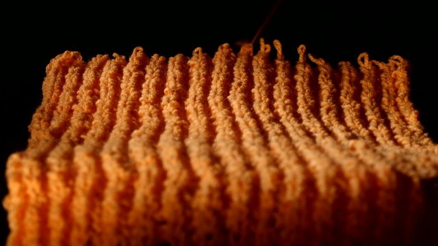 Unweave of big orange scarf on black background