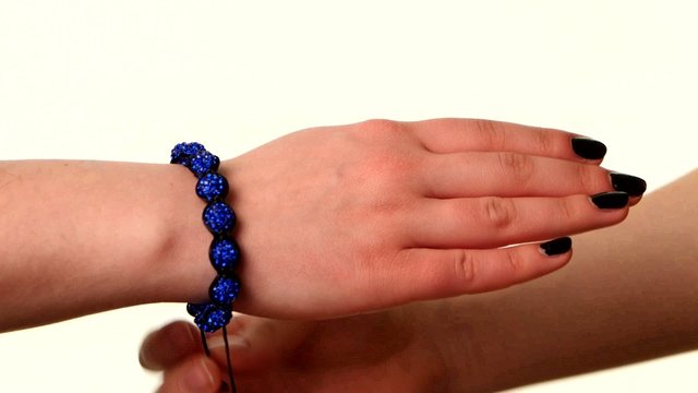 Woman shows popular bracelet shamballa on hand, white background