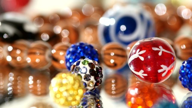 Different colors of beads on white background, rotation, close