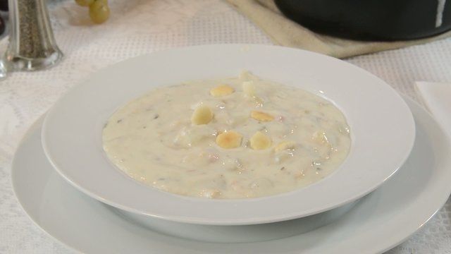Sprinkling saltine crackers into a bowl of clam chowder