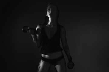 Black and white image of a young female fitness model posing.