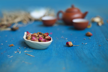 Rose buds on a plate with teapot and two cups.