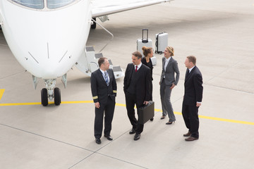 executive business team in front of corporate jet talking to pil