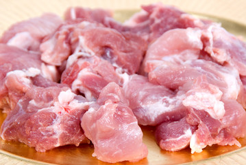 Peaces of fresh uncooked pork on a golden plate