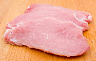 Three cuts of pork fillet on a wooden board