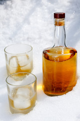 Bottle of brandy with two glasses in the snow