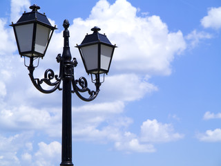 Fototapeta na wymiar Old street decorated lamppost against cloudy blue sky