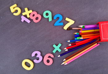 Colored pencils and school numbers on a black school board