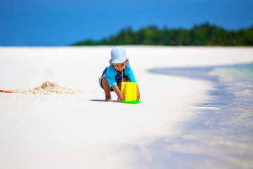 Little boy having fun on the beach while building a sand castle
