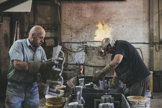 Two craftsmen preparing molds for casting in a foundry