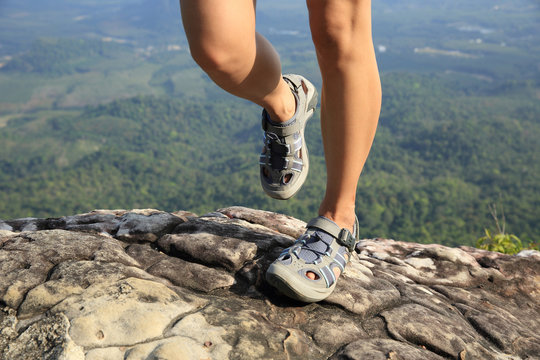 young woman hiker legs on mountain peak rock