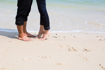 legs of kissing couple on beach