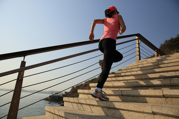 	young fitness woman running on seaside stone stairs