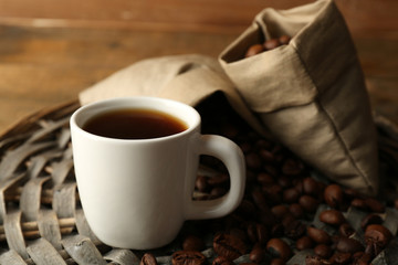 Cup of coffee with beans on rustic wooden background