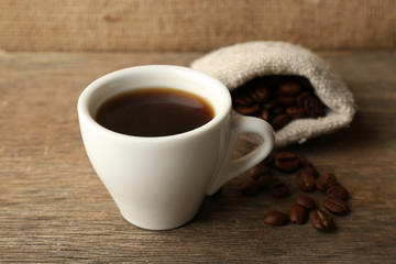 Cup of coffee with beans on rustic wooden background