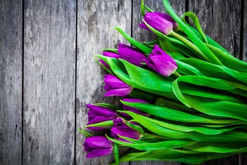 Fototapeta premium bouquet of purple tulips on a rustic background