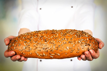 Fresh bread in female hands on light blurred background