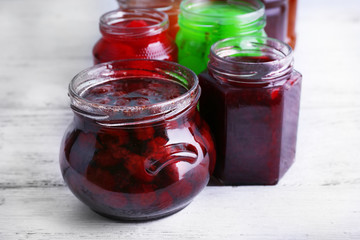 Fototapeta na wymiar Homemade jars of fruits jam on color wooden planks background