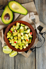 Salad with apple and avocado in bowl on tray on table close up