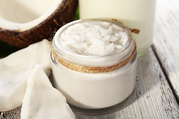 Fresh coconut oil in glassware on color wooden table background