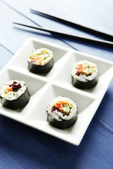 Vegetable sushi rolls on plate on color wooden background