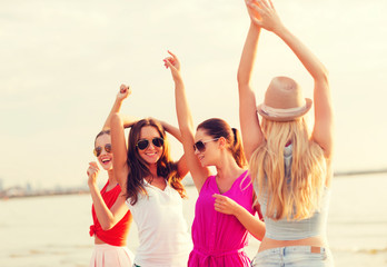 group of smiling women dancing on beach