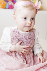 portrait of sitting toddler girl wearing pink dress