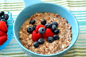 A bowl of oatmeal topped with blueberries and raspberries