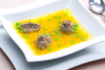 homemade liver dumplings in chicken soup with carrots and peas