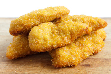 Golden fried chicken strips on wood board.