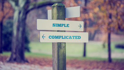 Rustic wooden sign in an autumn park with the words Simple - Com