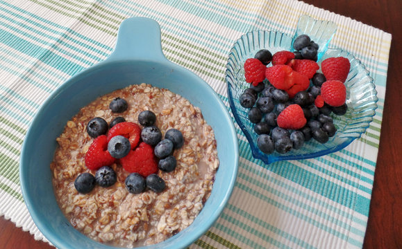 A bowl of oatmeal topped with blueberries and raspberries