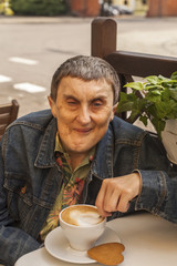 Portrait of elderly disabled man with cerebral palsy, at cafe.