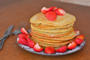 Stack of sweet pancakes with strawberry and icing sugar