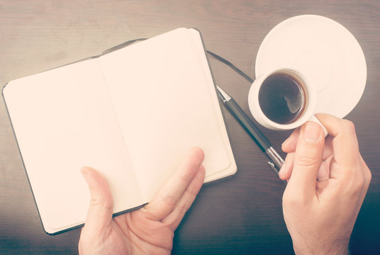 Man drinking coffee and checking his notebook